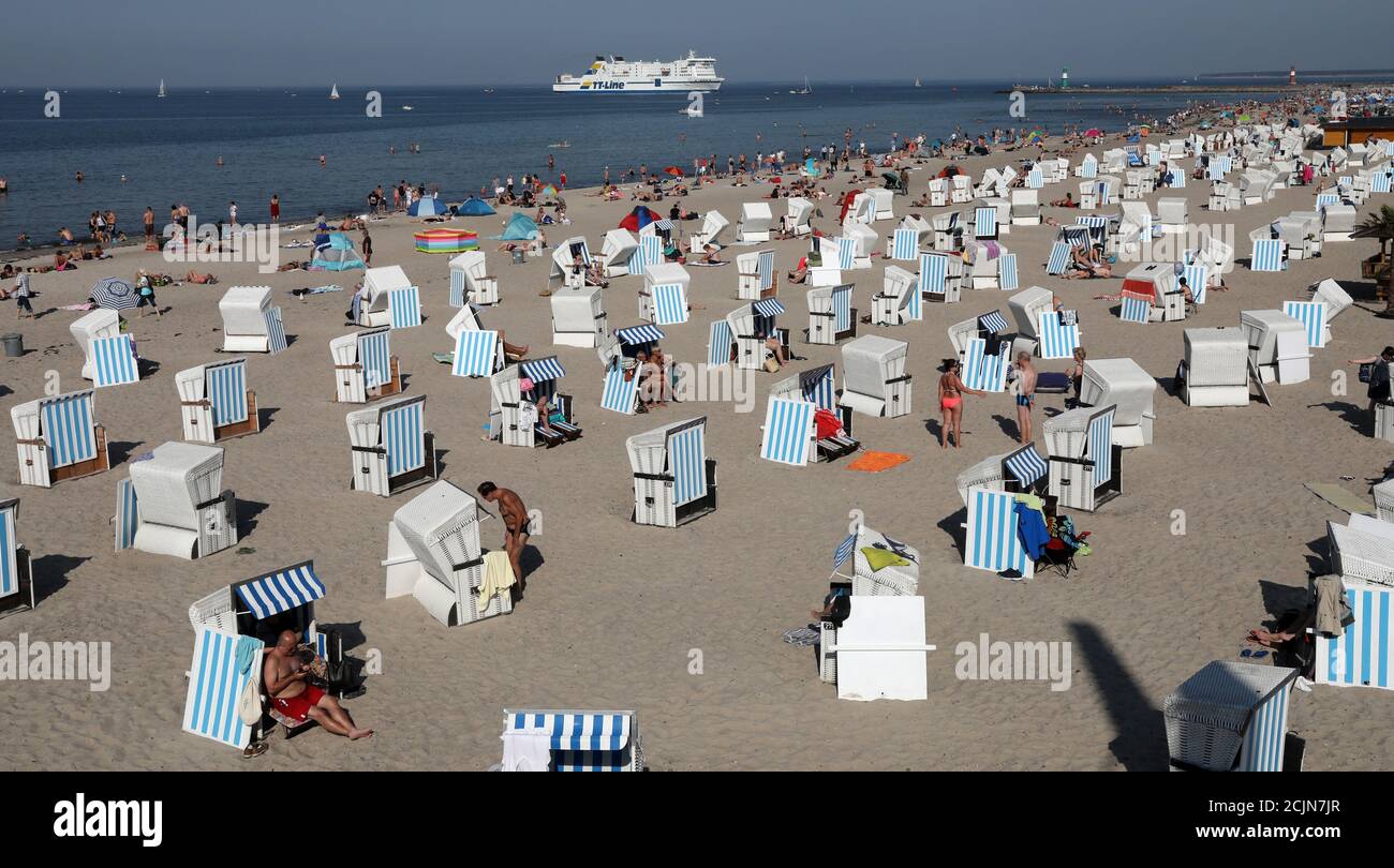 15 September 2020, Mecklenburg-Western Pomerania, Warnemünde: Swimmers enjoy the unusually warm late summer weather on the Baltic Sea beach, with the Swedish ferry 'Nils Holgersson' from TT-Line arriving in the background. The heat of September brings temperatures of up to 34 degrees in Germany, even in the 'cool' north temperatures reach the 30 degree mark. Photo: Bernd Wüstneck/dpa-Zentralbild/dpa Stock Photo