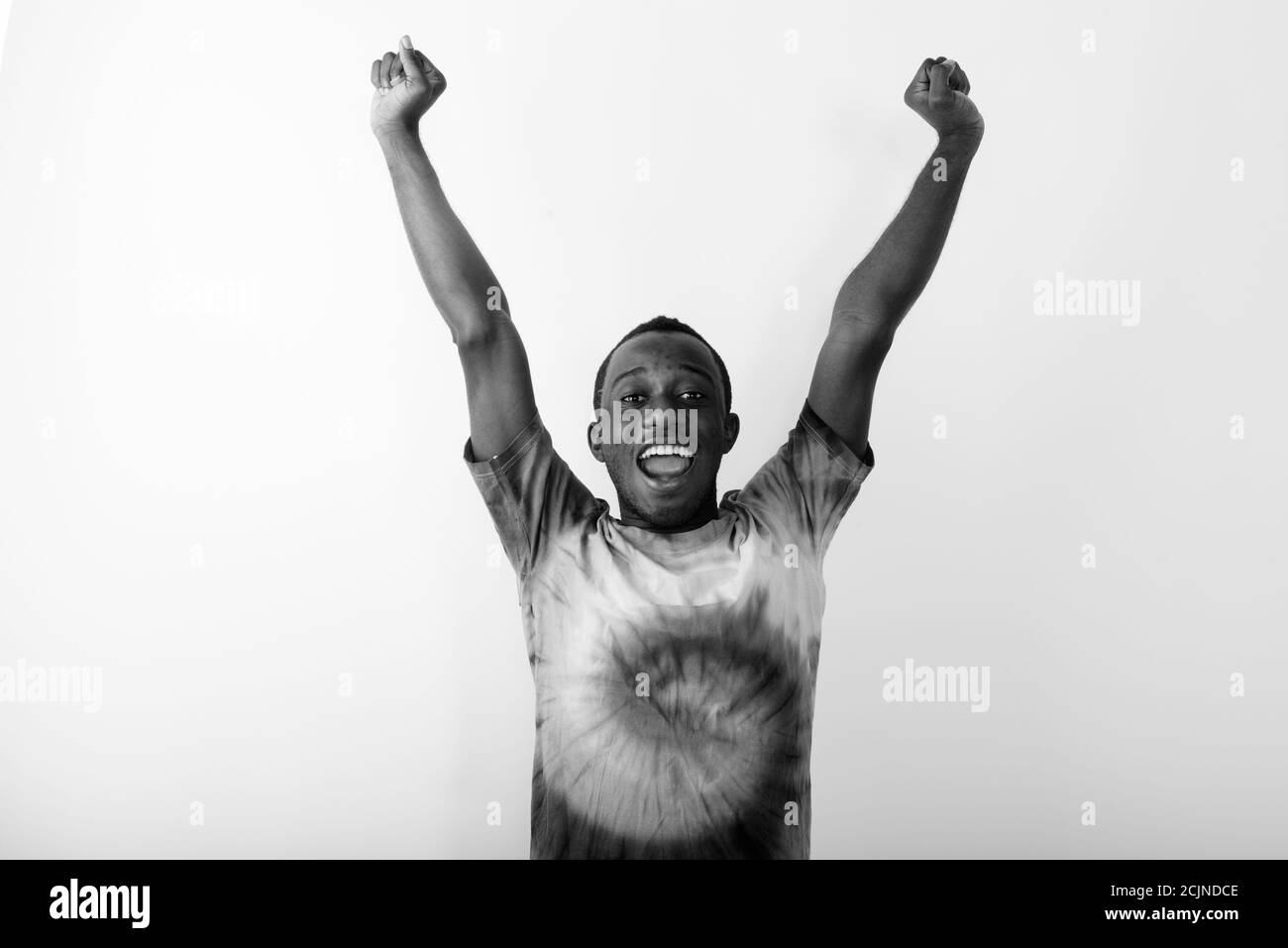 Studio shot of young happy black African man with both arms raised up ...