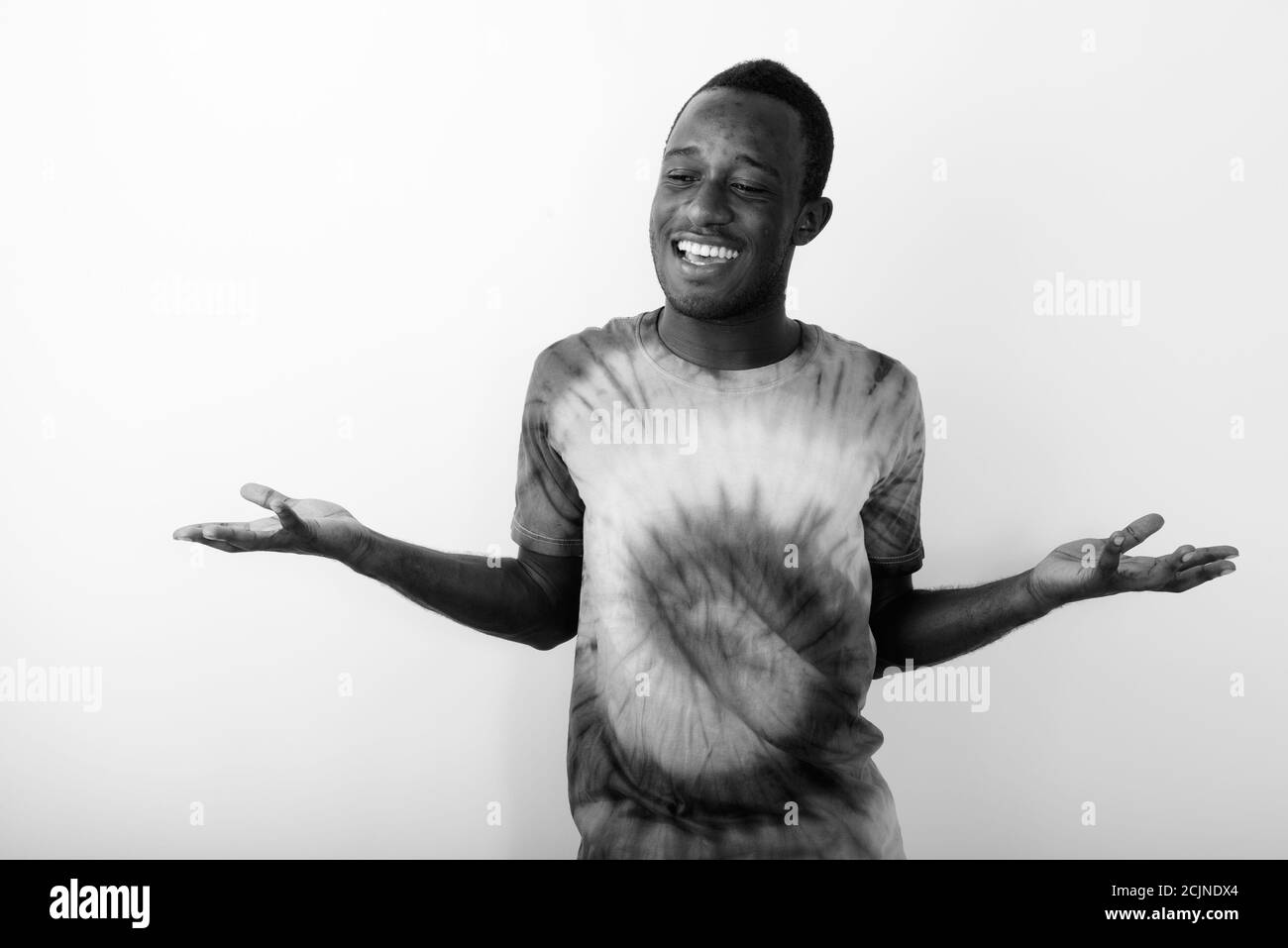 Studio shot of young happy black African man shrugging shoulders against white background Stock Photo