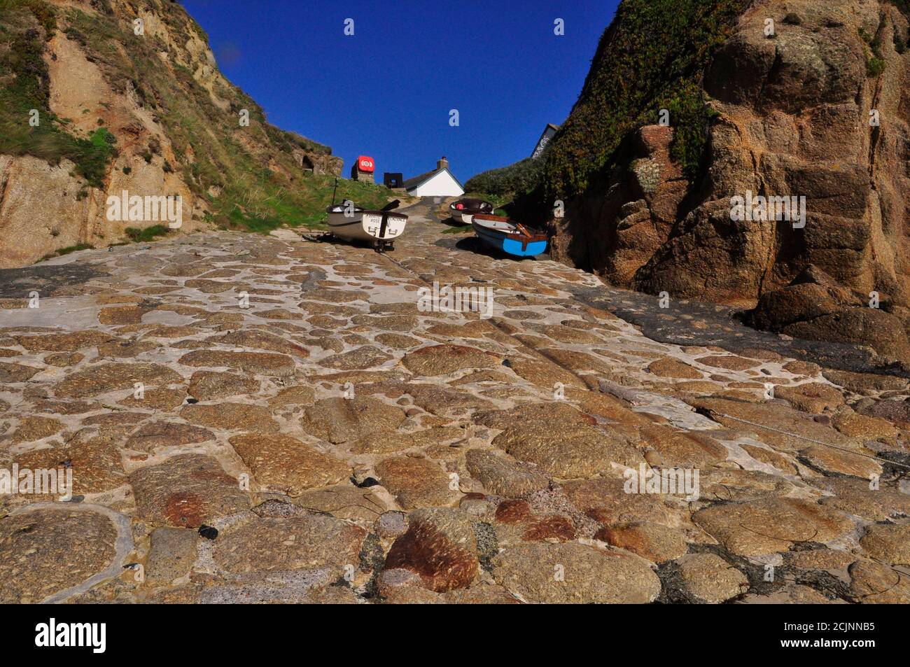 Steep granite slipway to the sea at Porthgwarra cove, with deep groves formed by hauling the fishing boats up the slope near Penzance in Cornwall, Eng Stock Photo