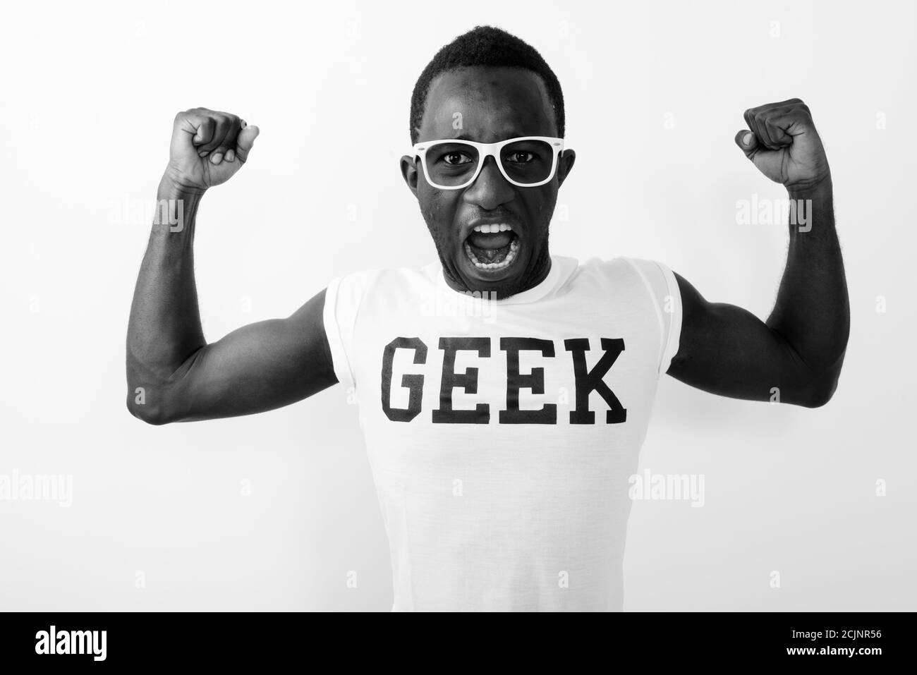 Young African nerd man wearing Geek shirt while flexing his arms and showing bicep muscles against white background Stock Photo