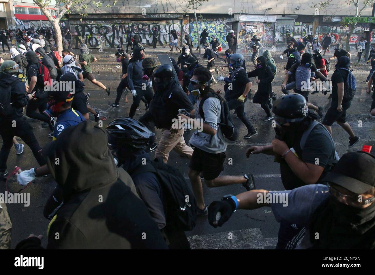Demonstrators run as they clash with riot police during anti-government protests in Santiago, Chile January 24, 2020. REUTERS/Edgard Garrido Stock Photo