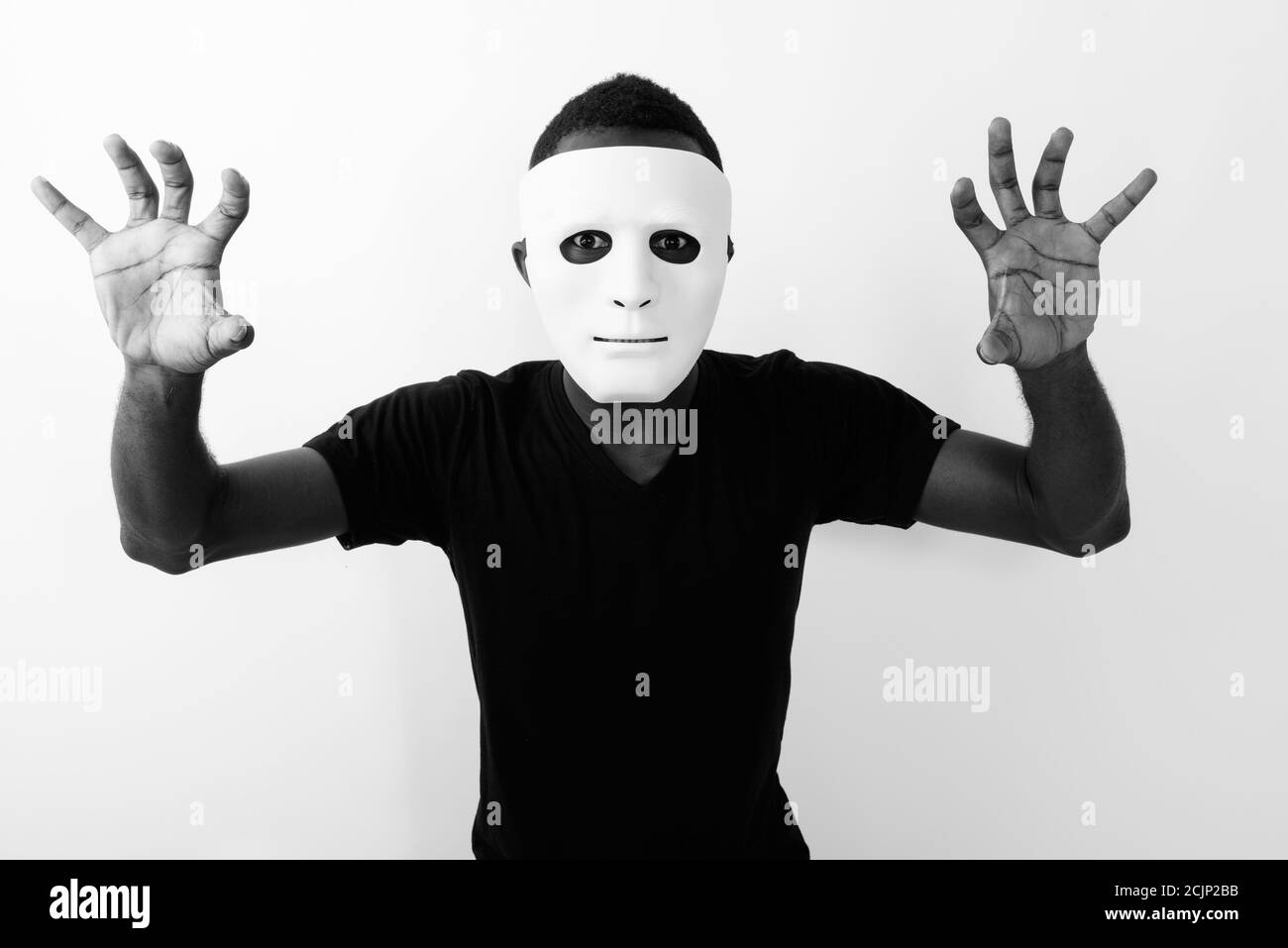 Studio shot of young black African man wearing mask and showing his both hands Stock Photo