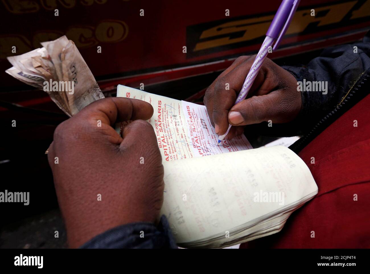 A public bus conductor writes receipts for passengers traveling to the countryside ahead of next week's general election in Nairobi, Kenya August 3, 2017. REUTERS/Thomas Mukoya Stock Photo