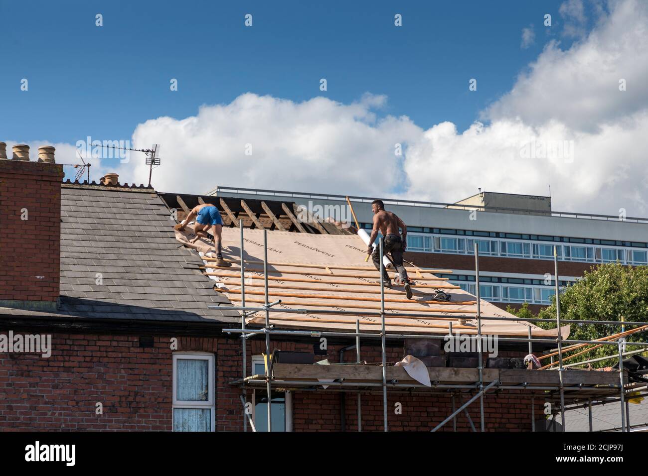 Men roofing house, laying felt under tiles, Newport, Wales, UK Stock