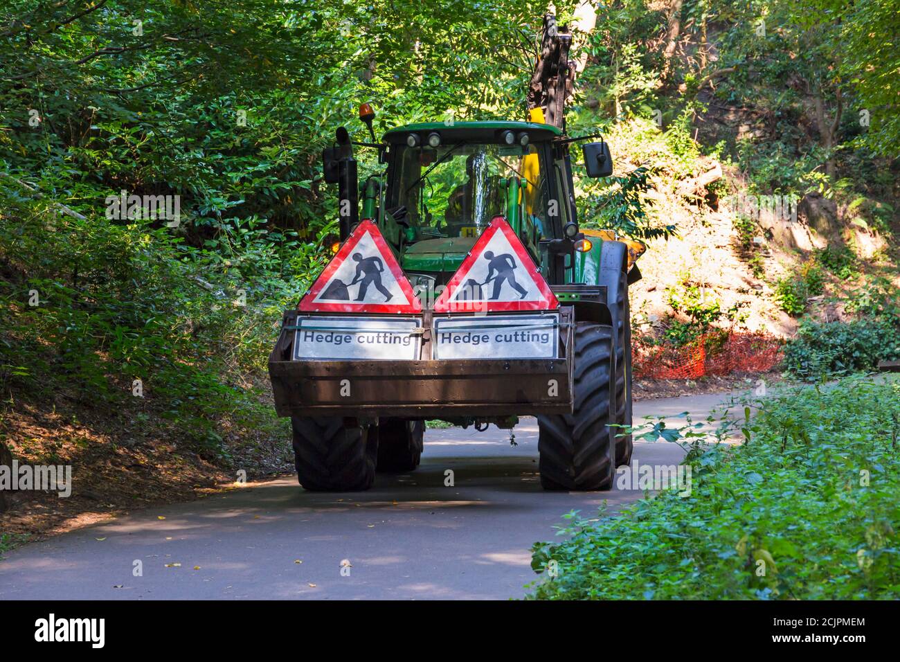 McConnel hedge cutter with hedge cutting signs on display driving through the chine at Alum Chine, Bournemouth, Dorset UK in September Stock Photo