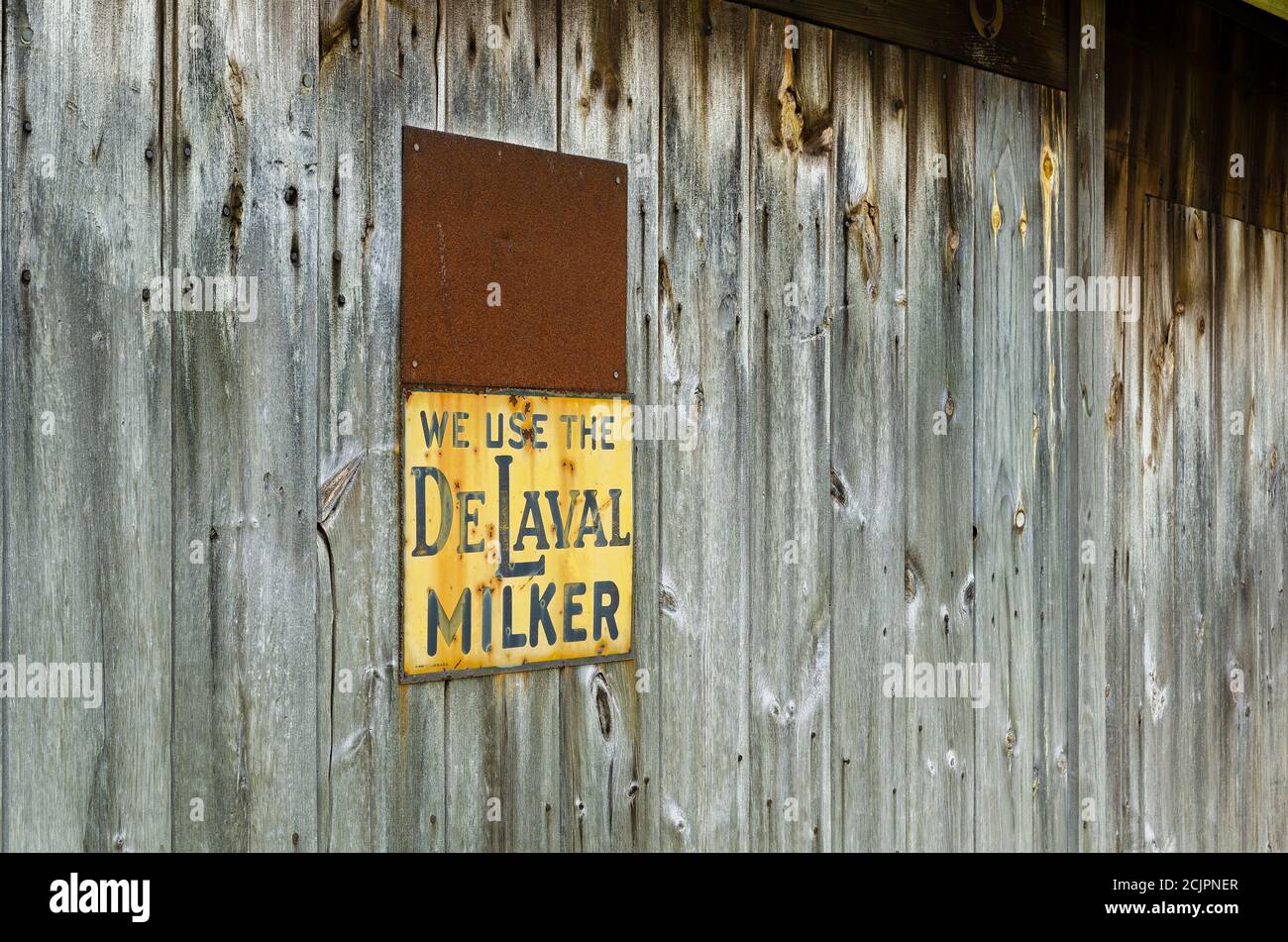 Rustic grey barn siding with two metal signs, knots, nails and rust. Stock Photo