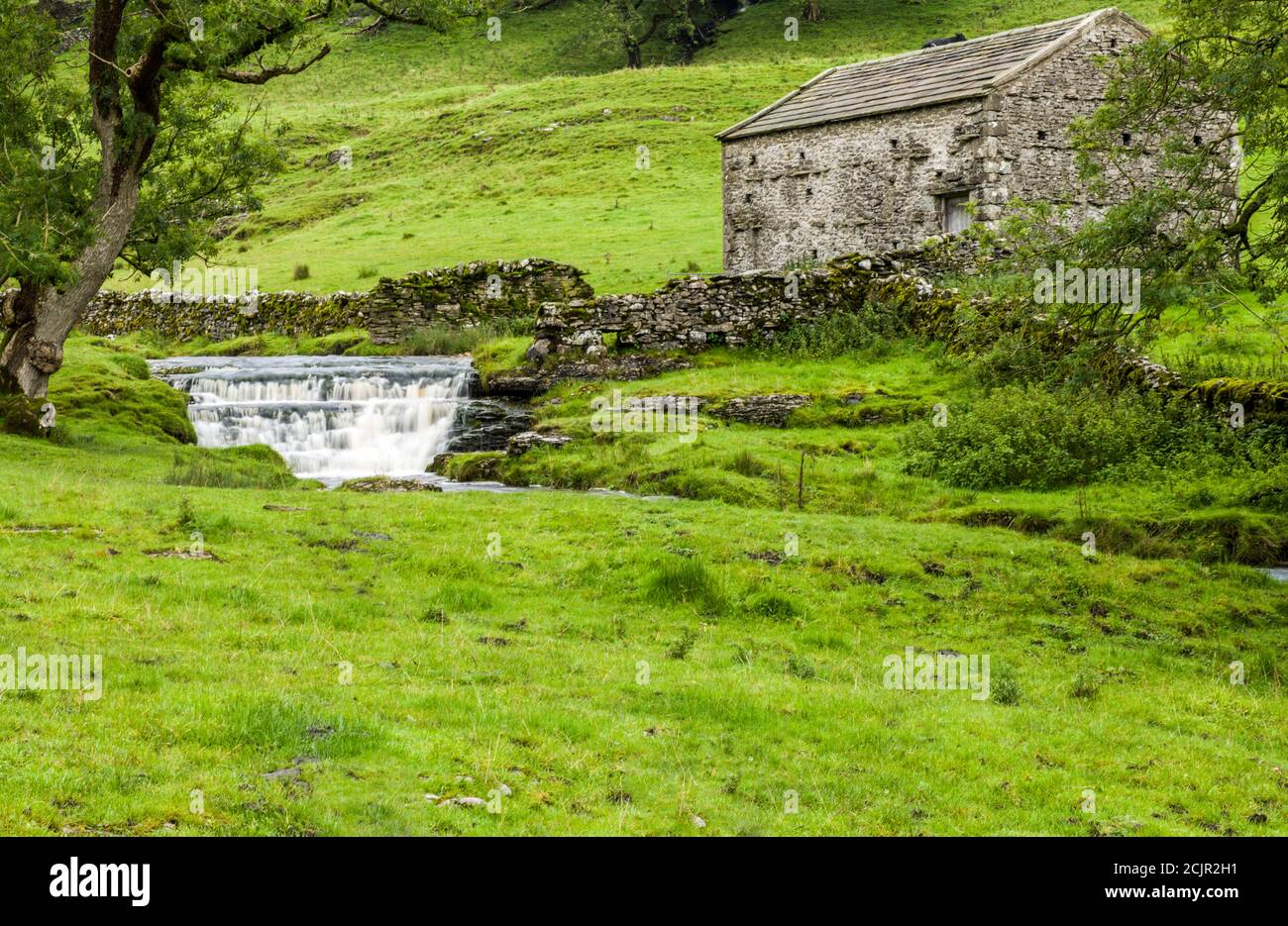 Waterfall and Dales barn at Cray, a small outpost on the road out of Upper Wharfedale to Bishopdale in the Yorkshire Dales National Park. Stock Photo