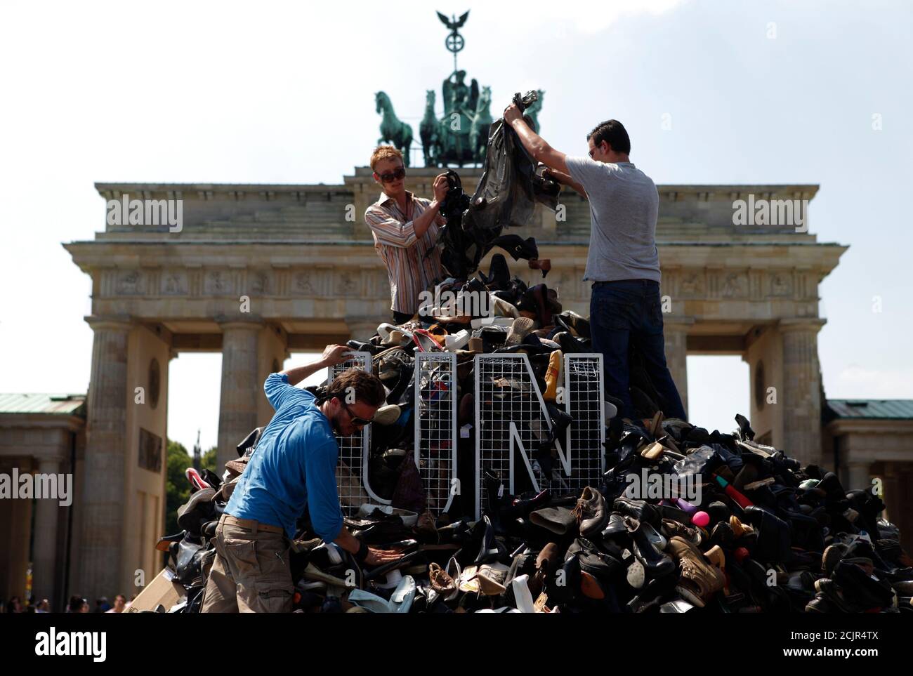 People pile up shoes to build the monument 'Pillar of Shame' in front of the Brandenburg Gate in Berlin, July 10, 2010, commemorating the 1995 mass murder of Muslim men and boys in the town of Srebrenica. The Society for Threatened Peoples has collected some16,744 shoes from Bosnia, Austria, Switzerland and Germany to build the monument is to draw attention to the failure of the United Nation (UN) to prevent the killing of 8372 refugees who died during the Bosnian War in an area that was declared a UN safe zone.  REUTERS/Thomas Peter (GERMANY - Tags: POLITICS IMAGES OF THE DAY) Stock Photo