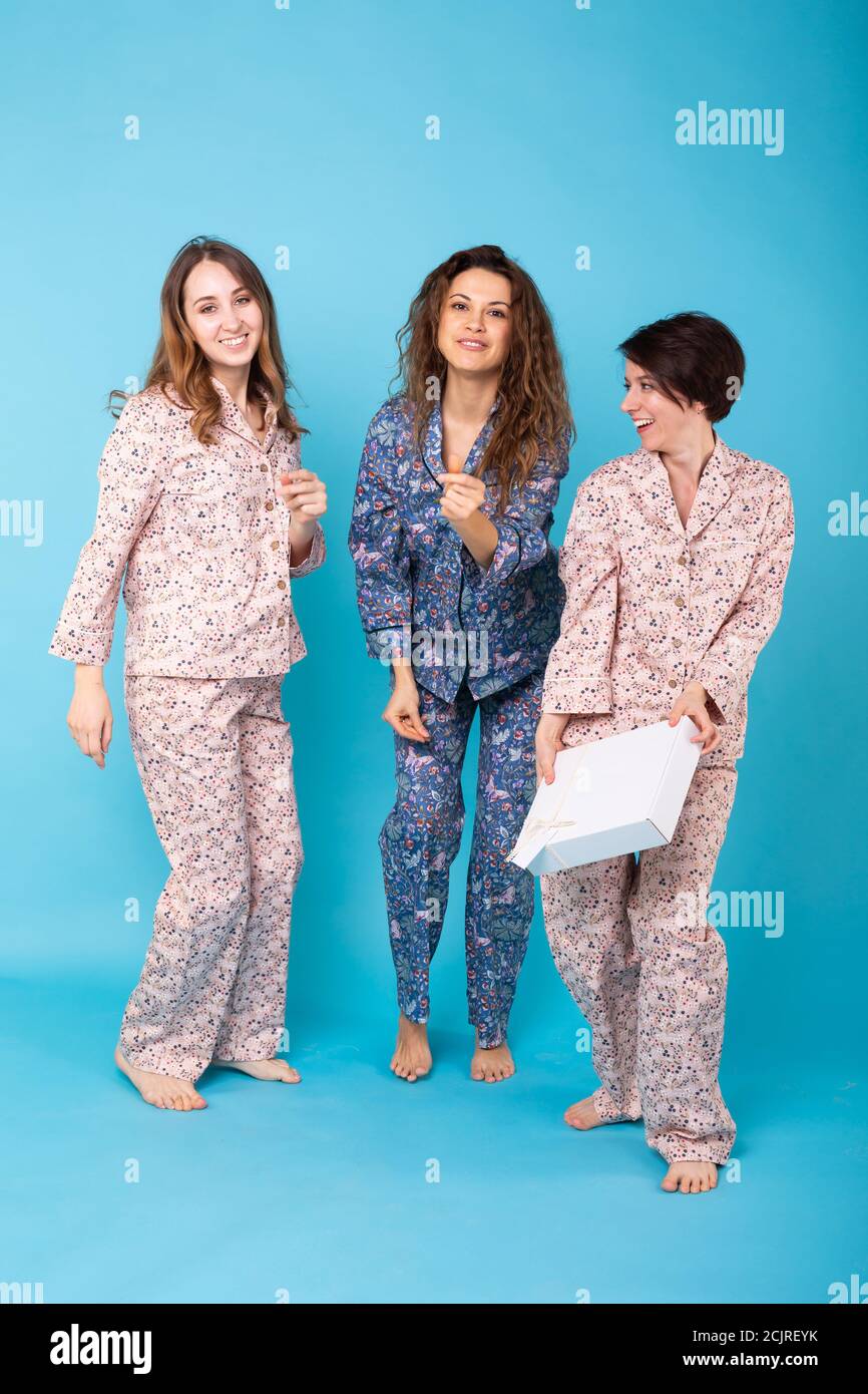 Portrait of three beautiful young girls wearing colorful pyjamas having ...