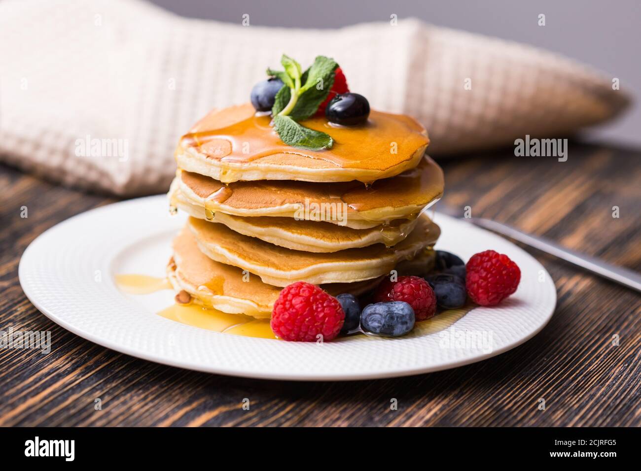 Pancakes with blueberries and raspberry and maple syrup on wooden ...