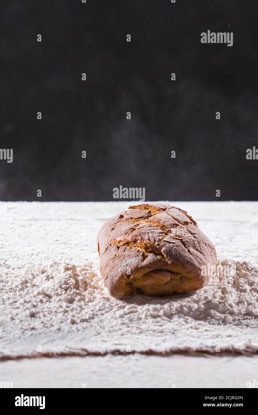 Traditional artisan rye bread loaf fall into flour. Dark background ...