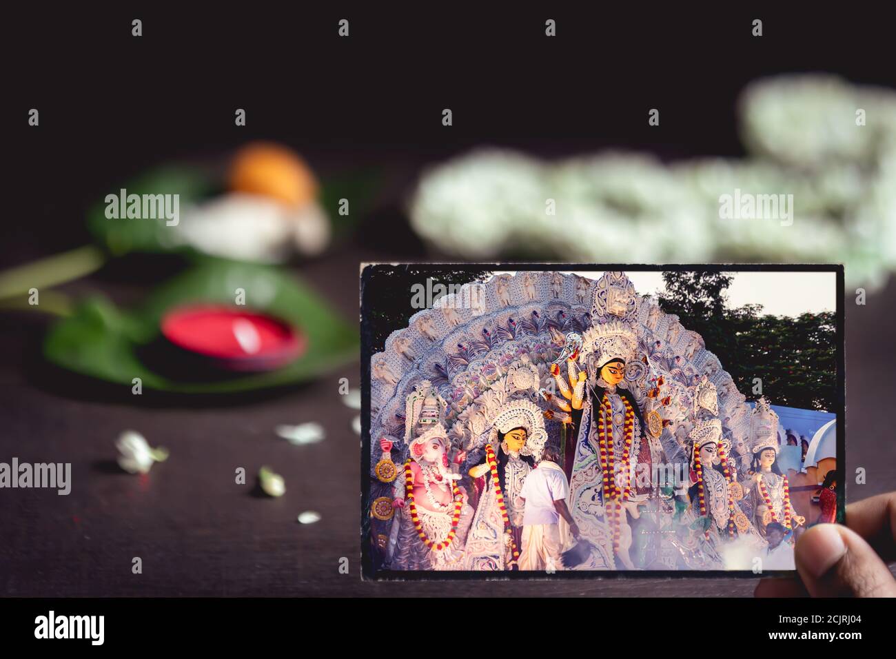 Durga Puja or Pooja background picture with copy space. Old photograph of Indian goddess Durga with flowers, kumkum, betel leaves for the rituals. Stock Photo