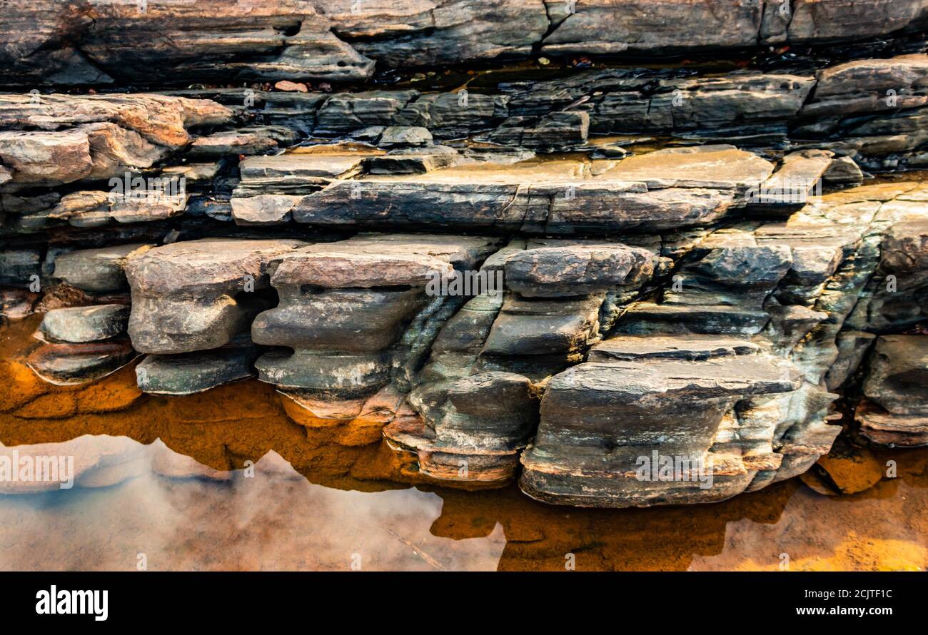 natural rock formation with water reflection at sea shore due to crashing waves at morning image is taken at om beach gokarna karnataka india. Stock Photo