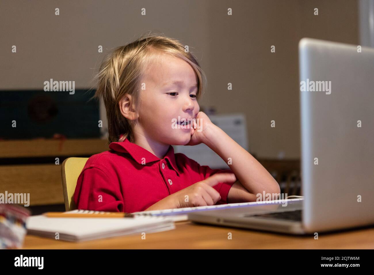 A young boy speaks with his kindergarten teacher on a laptop while