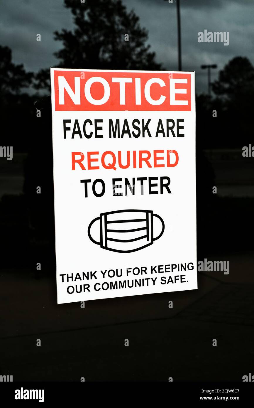 Face mask required to enter warning sign on the front door of a business in Alabama, USA during the Covid 19 pandemic. Stock Photo