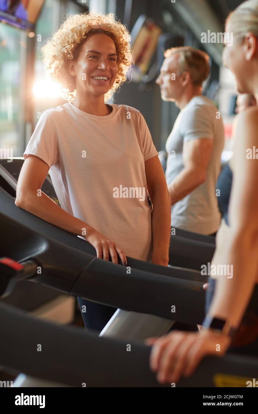 Happy beautiful woman talking to her friend during their sports training in gym Stock Photo