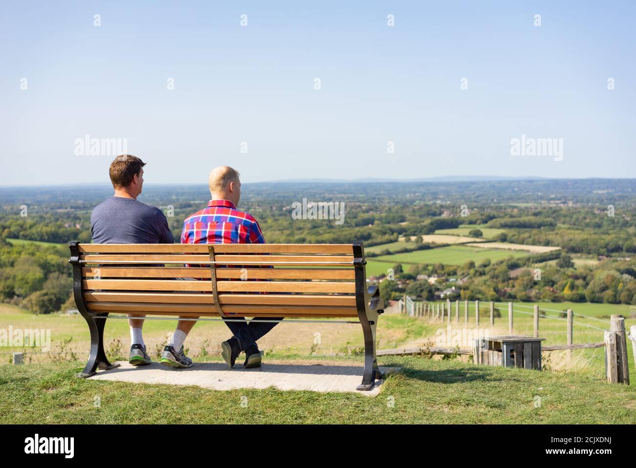 Two men sitting on a bench at the Jack and Jill Windmill location on the South Downs in East Sussex England Stock Photo