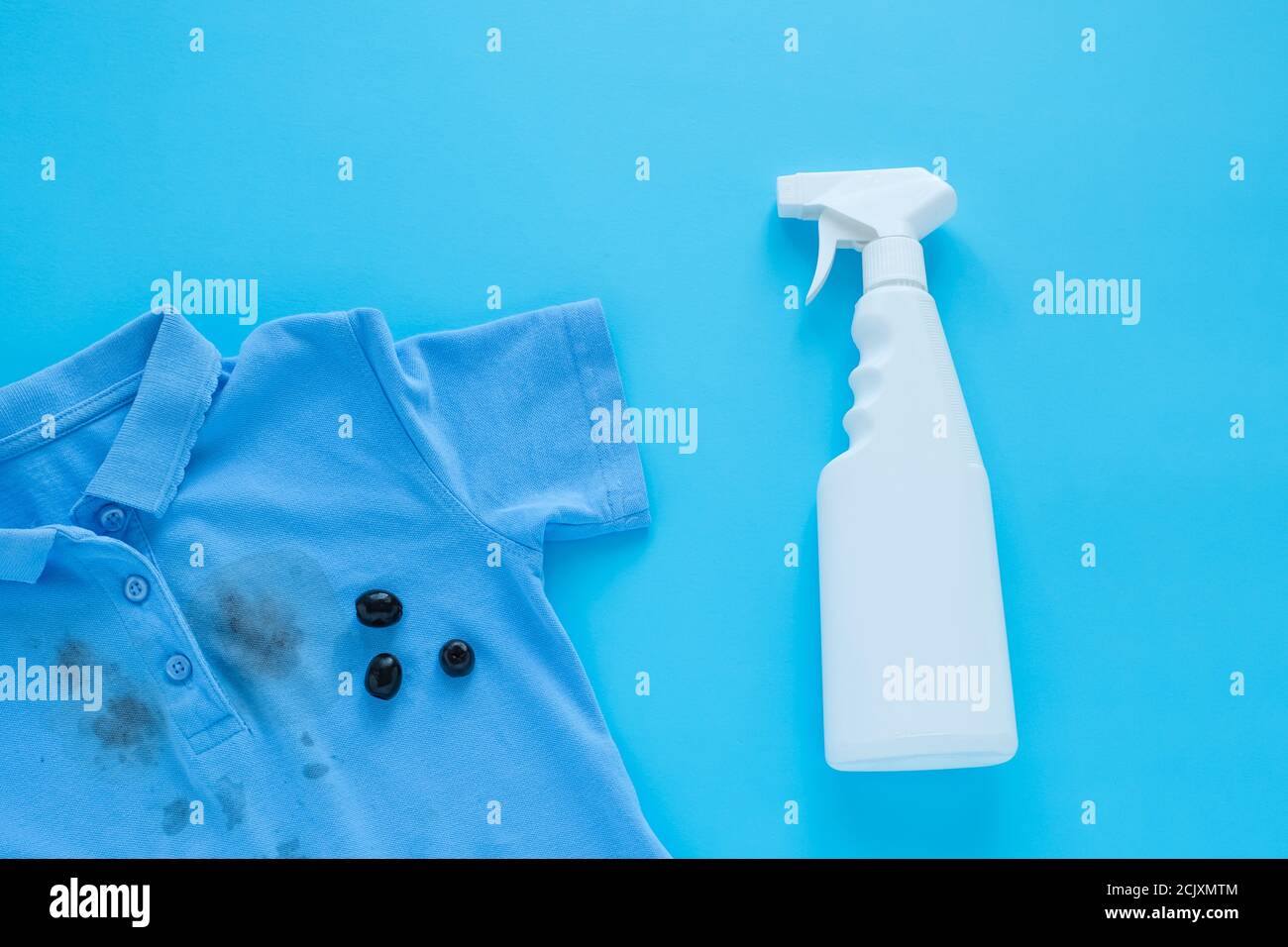 stains of dirty black olives on clothes and stain remover. Stain cleaners. Isolated on a blue background Stock Photo