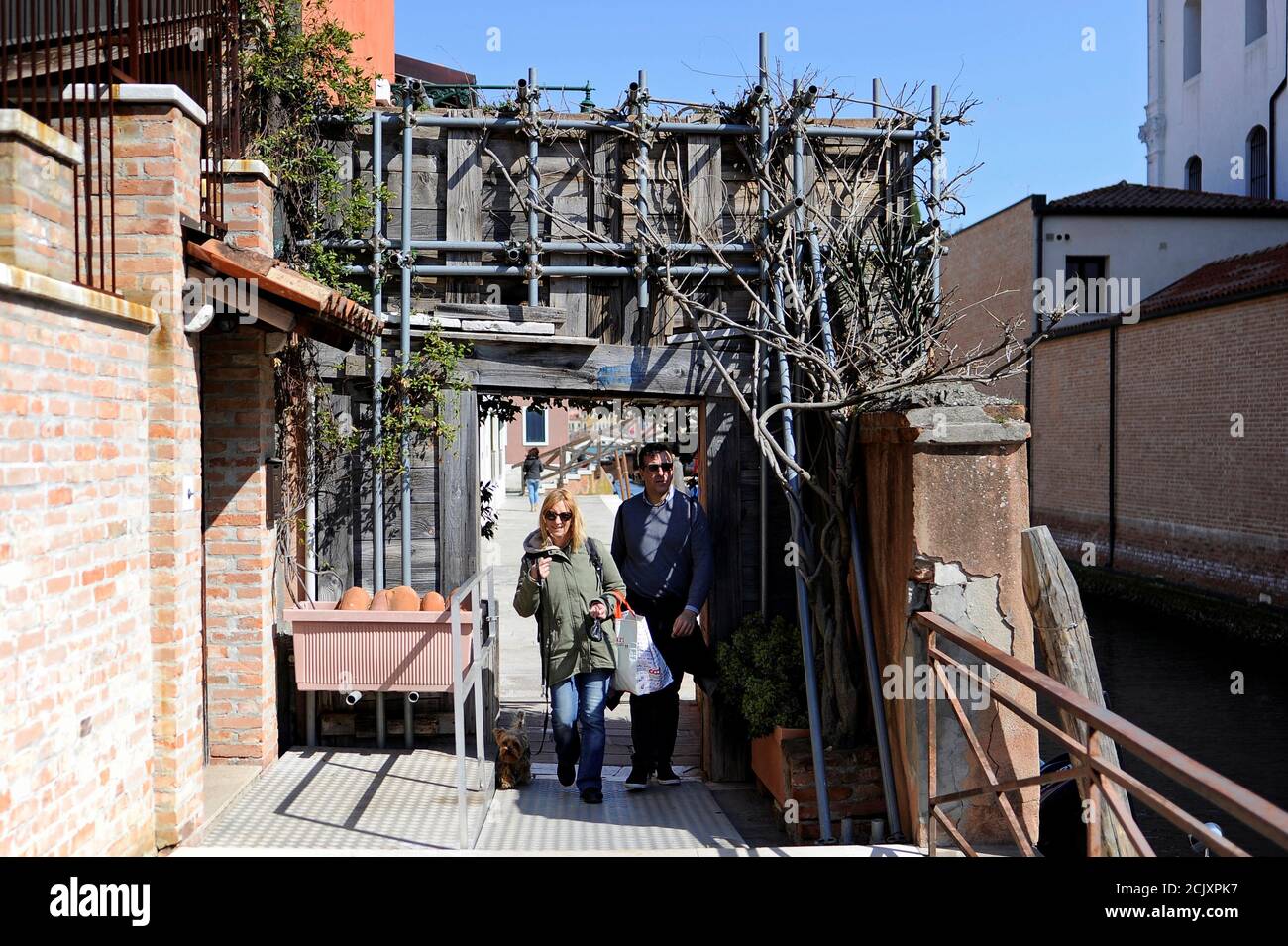 Patrizia Zaniol, 56, and spokesman of Social Assembly for the House (ASC) Nicola Ussardi, 41, who both live in illegally occupied apartments walk through the only entrance by land to the Casette neighbourhood where about 20 apartments are illegally occupied, in Venice, Italy, April 1, 2019. "If the police try to enter the neighborhood by land we'll block the passage. We are prepared to do anything to defend our apartments, even physical confrontation", Ussardi said. Picture taken April 1, 2019. REUTERS/Guglielmo Mangiapane Stock Photo