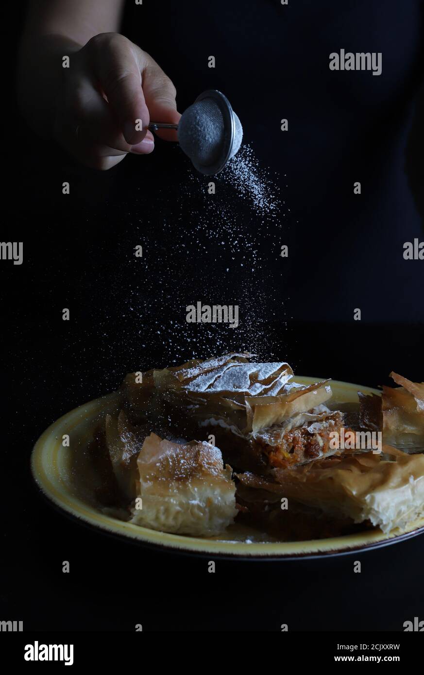 Sprinkled icing sugar on sweet pumpkin pie in phyllo dough. Halloween and fall festivities. Stock Photo