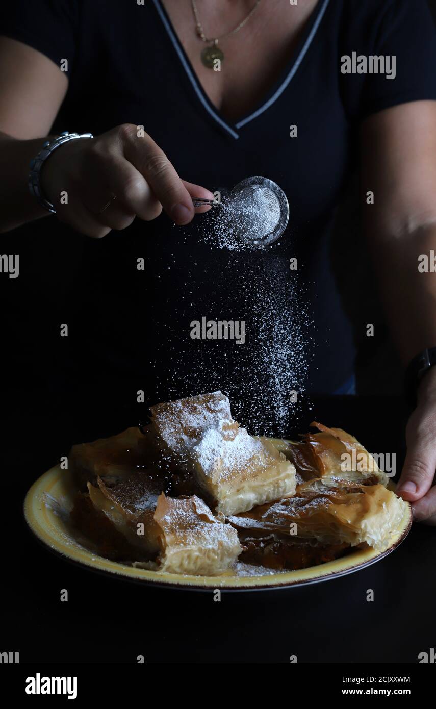 Sprinkled icing sugar on sweet pumpkin pie in phyllo dough. Halloween and fall festivities. Stock Photo