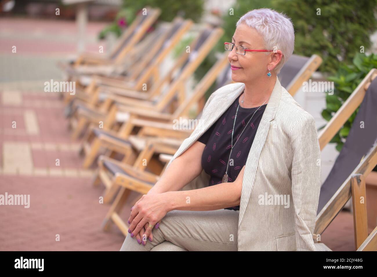 a pleasant mature woman in stylish clothes is waiting the concert ouside. side view photo Stock Photo
