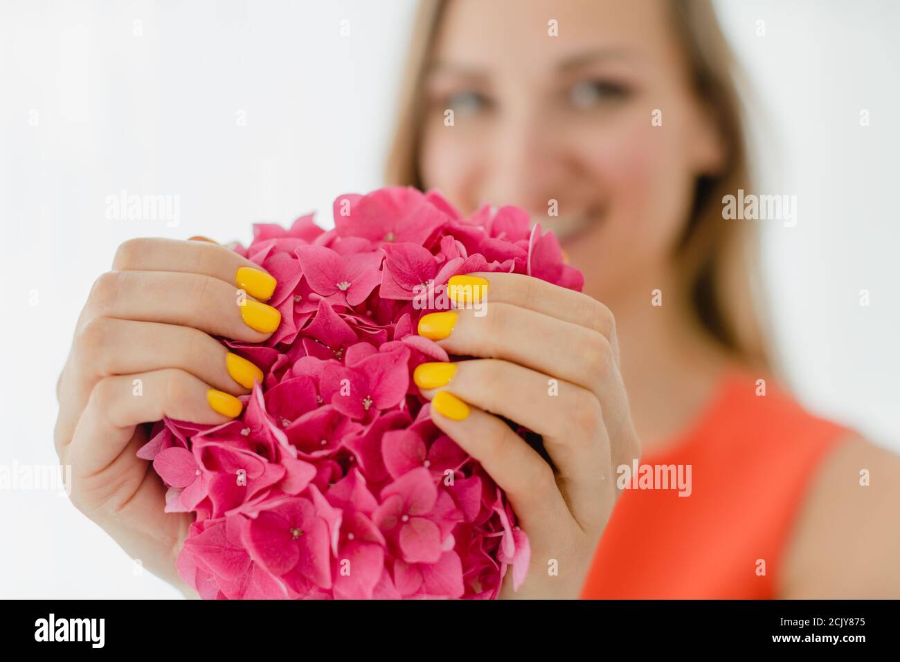 Women with manicured nails in yellow holding a flower Stock Photo