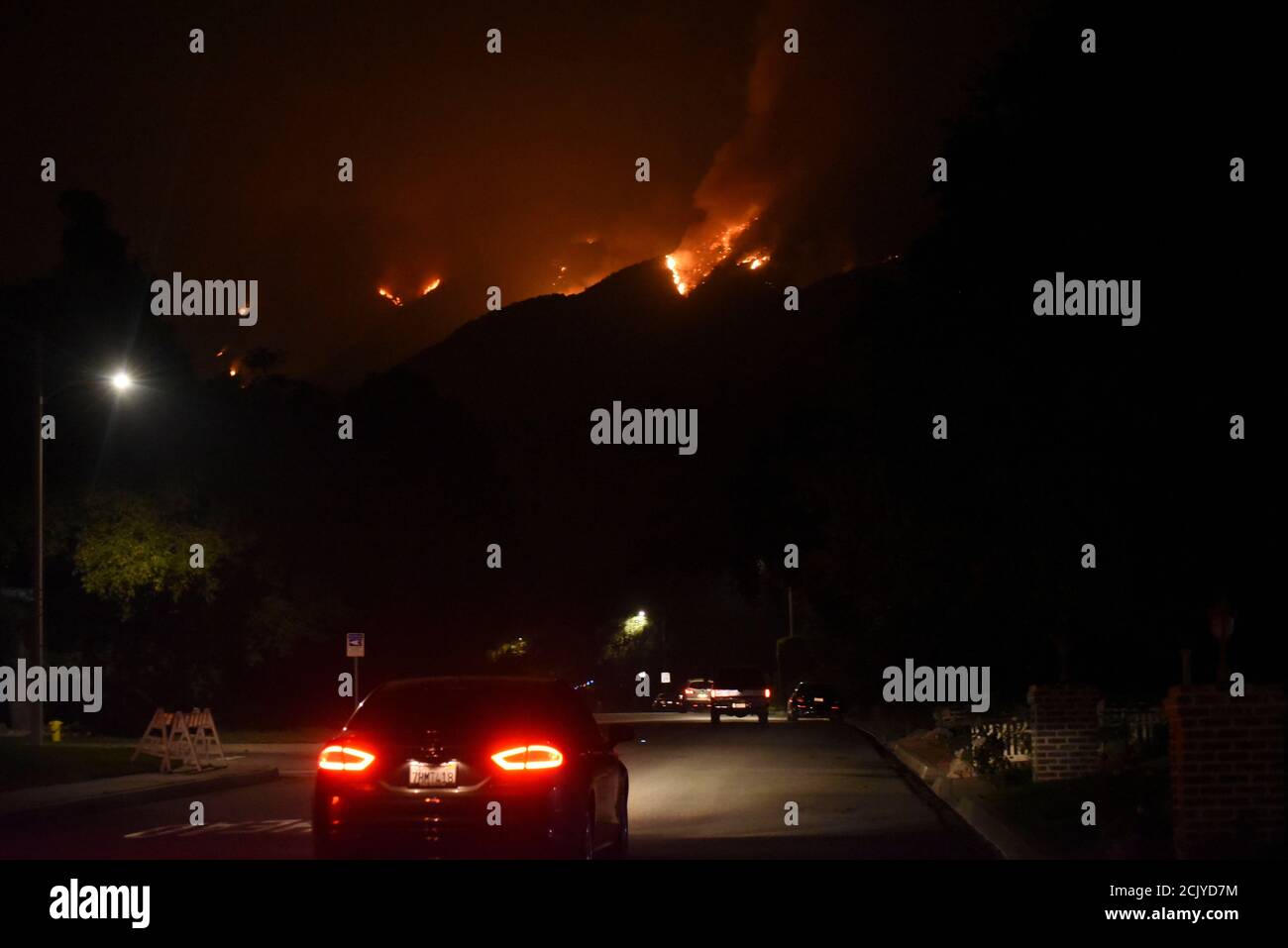 Arcadia, California, USA. 12th Sep, 2020. The Bobcat Fire rages across the hills, as residents below on Highland Oaks Dr. slowly travel up and down their streets in the errie light of a normally dark street. The neighborhood is on standby to evacuate. Stock Photo