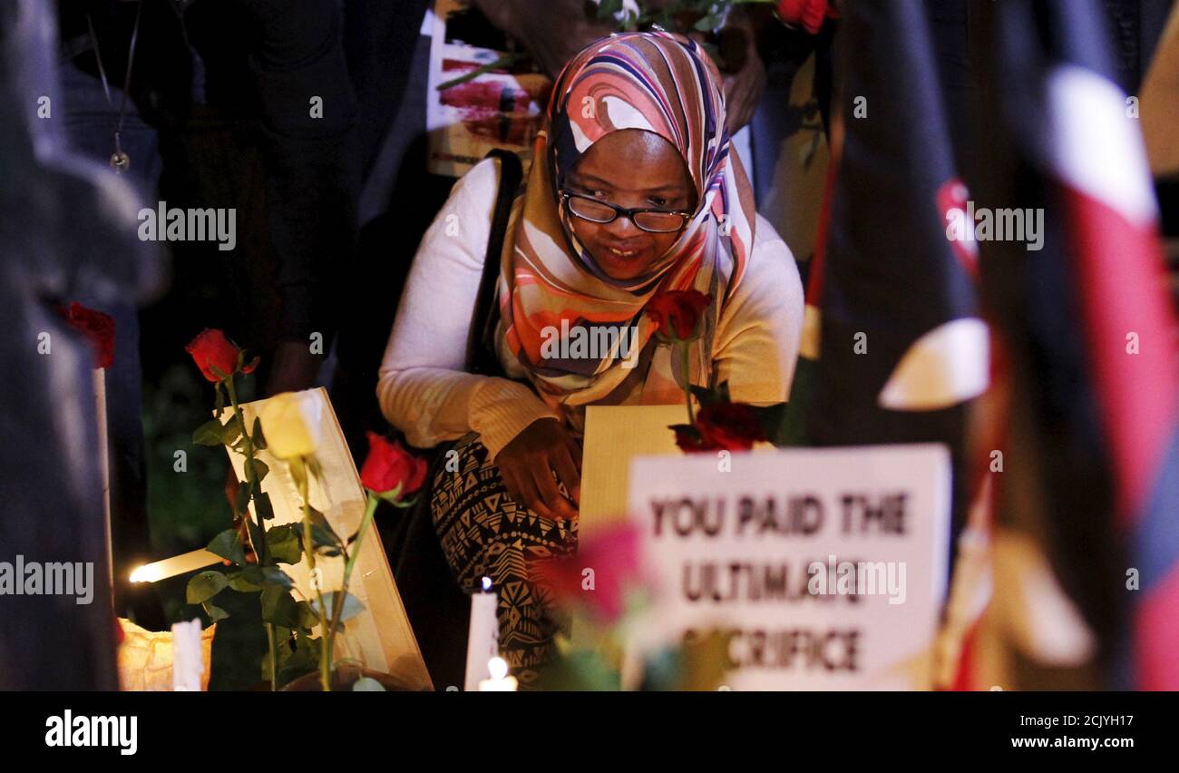 A woman lights a candle near a replica of a gun and helmets placed on the ground to symbolise Kenyan soldiers serving in the African Union Mission in Somalia (AMISOM) who were killed during an attack last week, at a memorial vigil within the 'Freedom Corner' in Kenya's capital Nairobi, January 21, 2016. Al Shabaab, which is aligned with al Qaeda, said its fighters killed more than 100 Kenyan soldiers when they overrun the base in Ceel Cadde, near the Kenyan border, on Jan 15. REUTERS/Thomas Mukoya Stock Photo