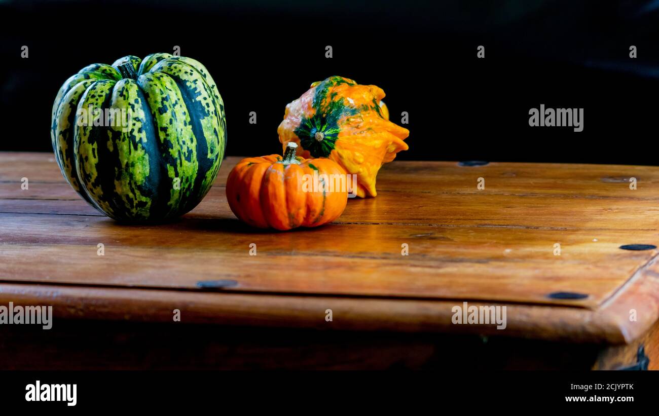 Variety of pumpkins on rustic wooden table and plain black background ...