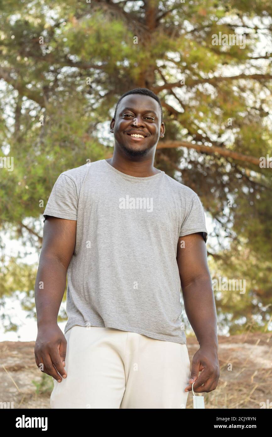 Closeup shot of a young Nigerian man in white cloth smiling with a green  tree on the background Stock Photo - Alamy