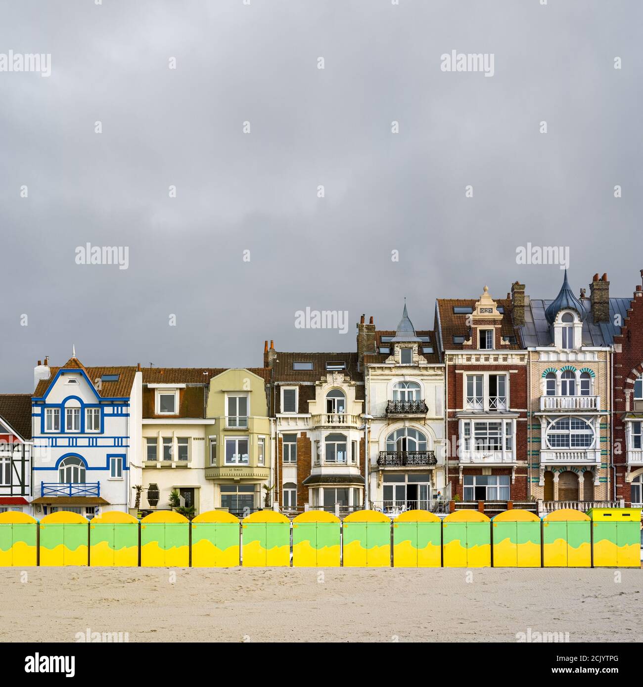 Colorful beach huts in front of historic seaside buildings Stock Photo