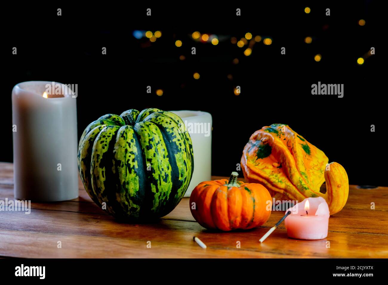 Variety of pumpkins and candles on rustic wooden table and black ...