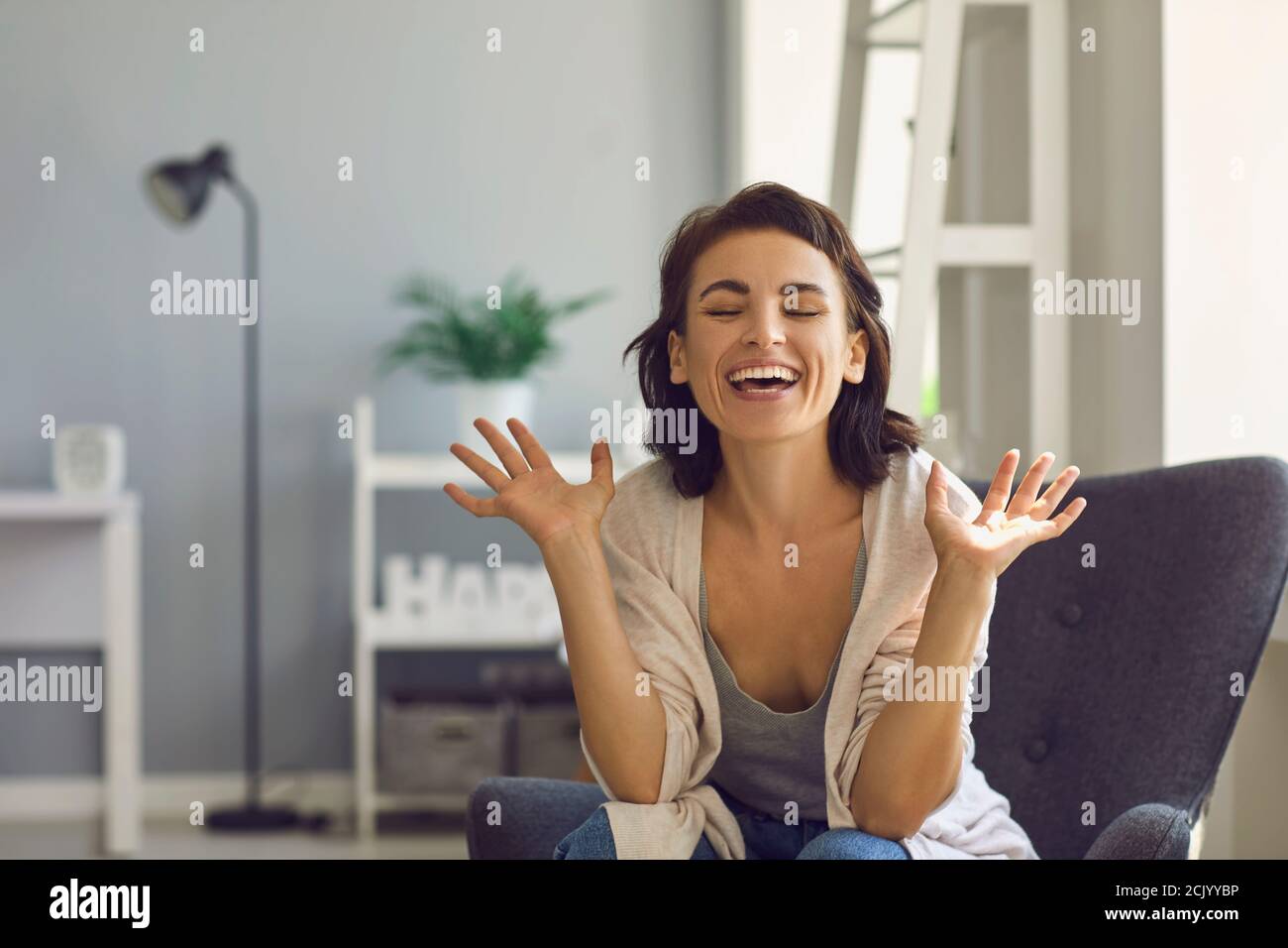 Young smiling woman expressing happiness during online meeting or teleconference from home Stock Photo