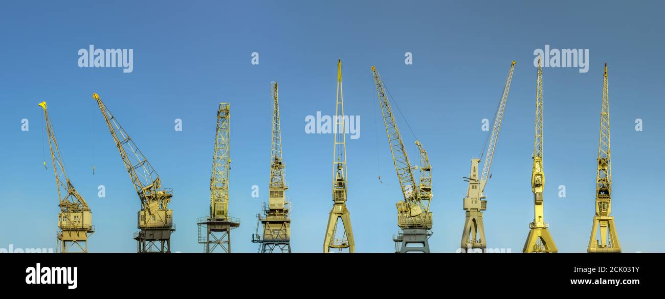 Row of majestic old harbor cranes in Antwerp with early morning sky. Stock Photo