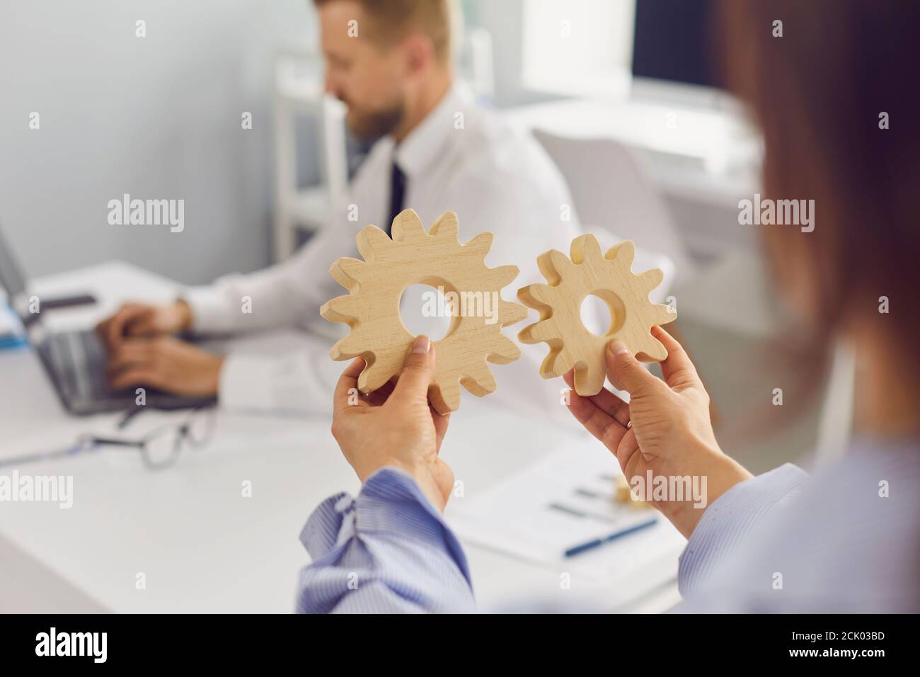 Company manager joining two cogwheels as metaphor for business system that works perfectly well Stock Photo