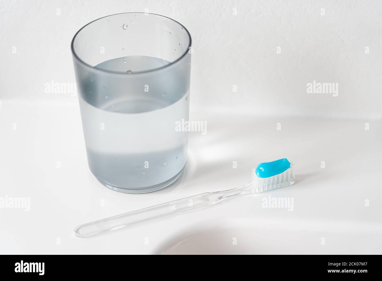 A white sink lies a toothbrush with blue toothpaste and a toothbrush ...