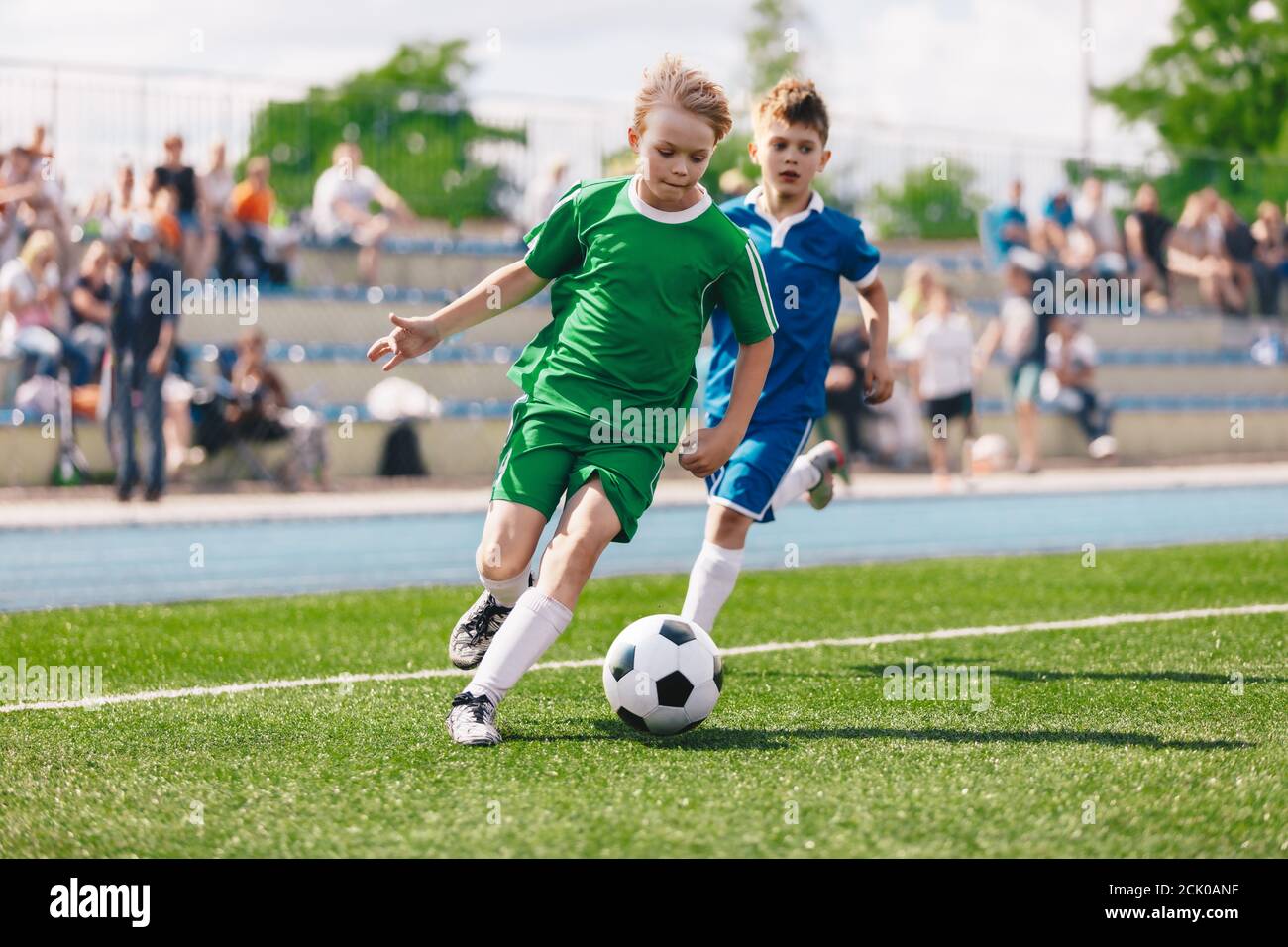 Young boys playing soccer game. Kids having fun in sport. Happy kids compete in football game. Running soccer players. Competition between players run Stock Photo
