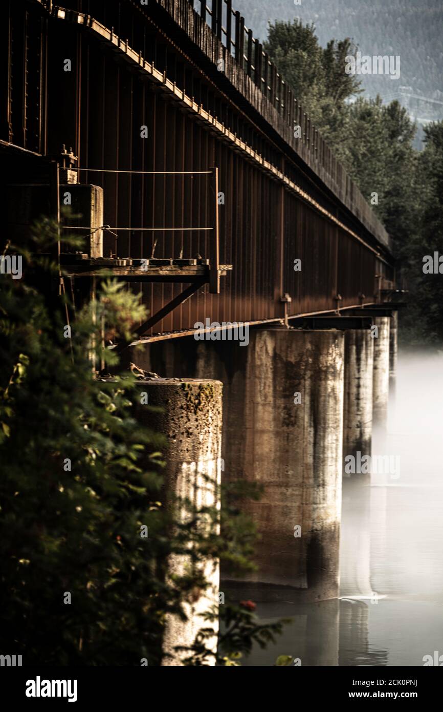 The Revelstoke CP Rail Line bridge over a foggy Columbia river Stock Photo