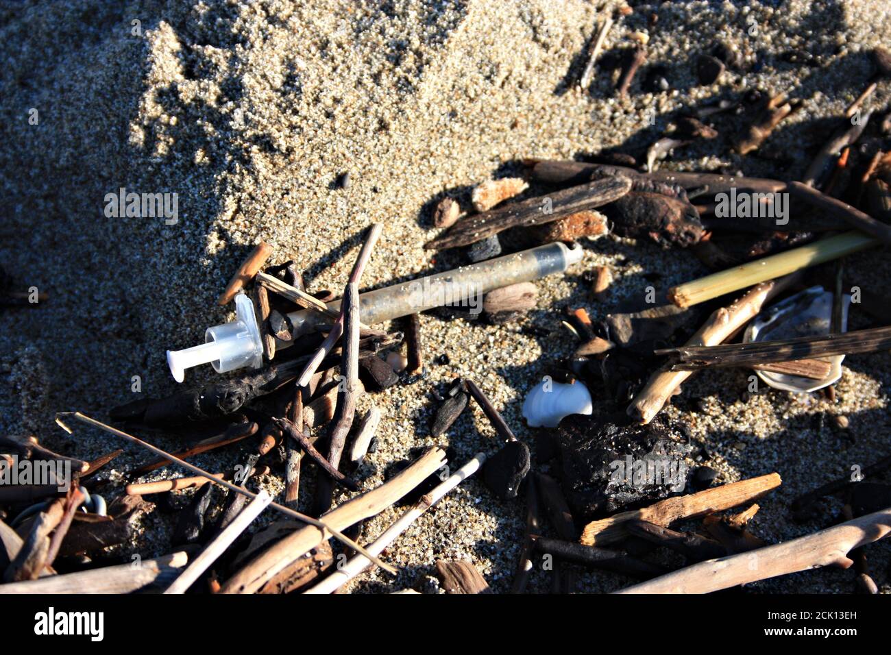 dangerous used syringes abandoned on the beach in the midst of other