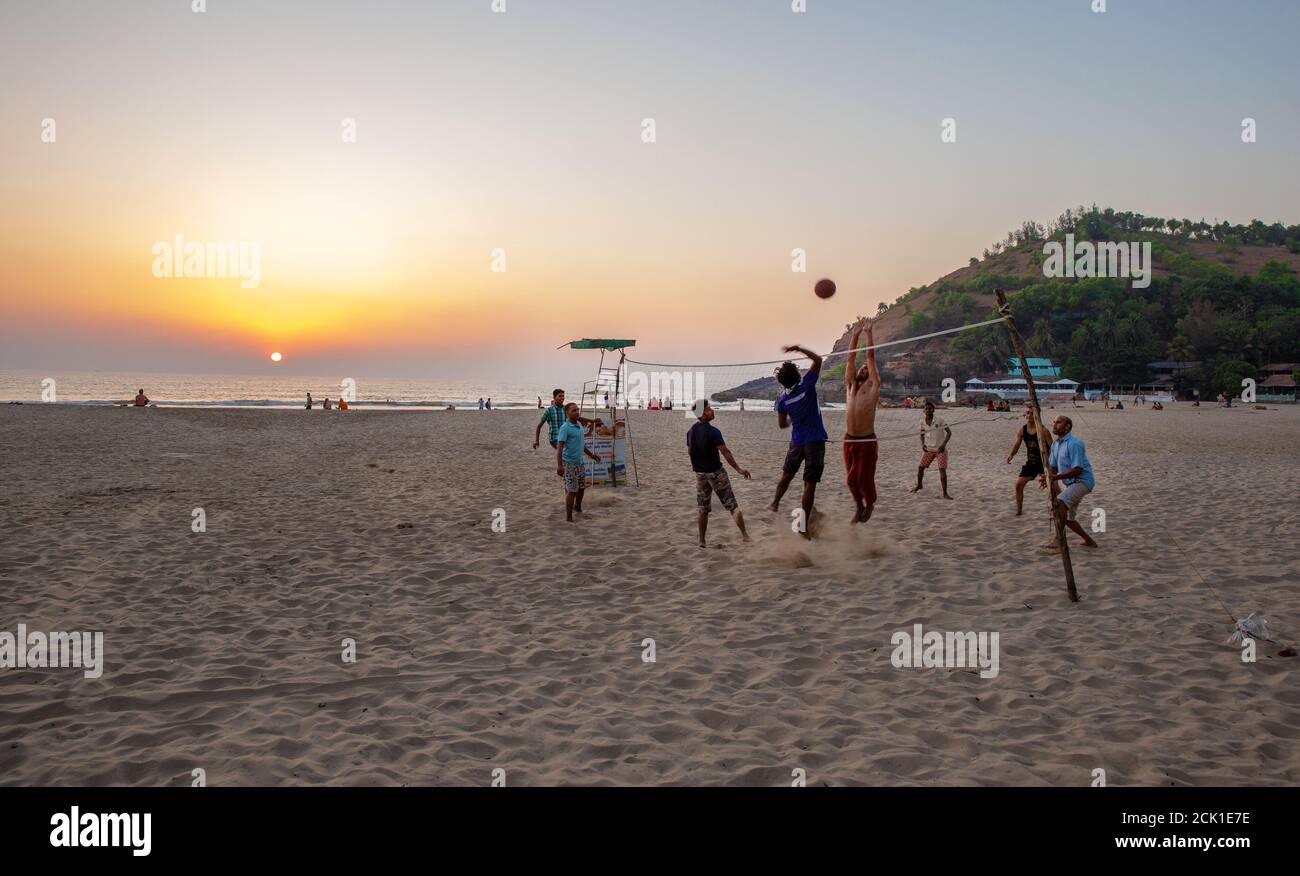 02/19/2019 Gokarna, India. Caucasian and Indian men playing volleyball on the beach  in sand  - amazing sunset Stock Photo