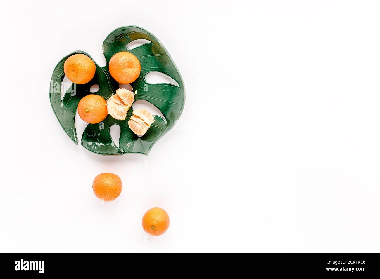 Ceramic plate-leaf Monstera with tangerines isolated on white background. Flat lay, top view.  Stock Photo