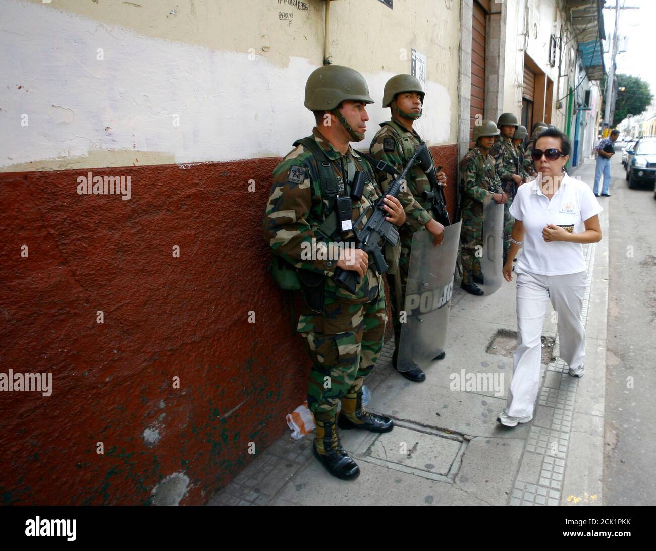 A woman walks past soldiers standing guard in Tegucigalpa July 7, 2009. Ousted Honduran President Manuel Zelaya said on Tuesday he accepted the mediation of Costa Rican President Oscar Arias to try to solve his country's political crisis following the June 28 coup that ousted him. REUTERS/Henry Romero (HONDURAS CONFLICT MILITARY POLITICS) Stock Photo
