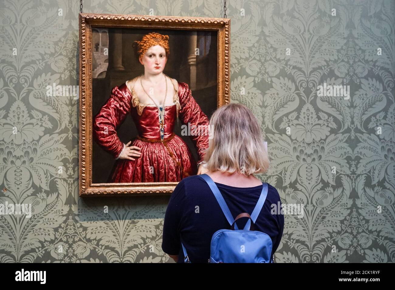 Young woman looking at painting, Portrait of a Young Woman by Paris Bordone, at the National Gallery in London, England United Kingdom UK Stock Photo