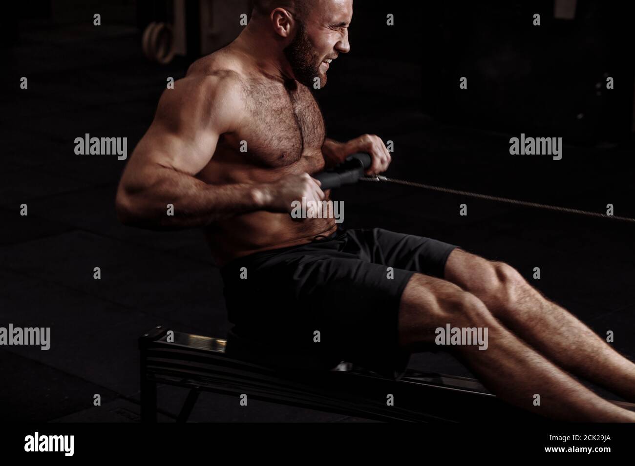 a tensing strong muscular man sitting on the sport equipment. hardworking sportsman Stock Photo