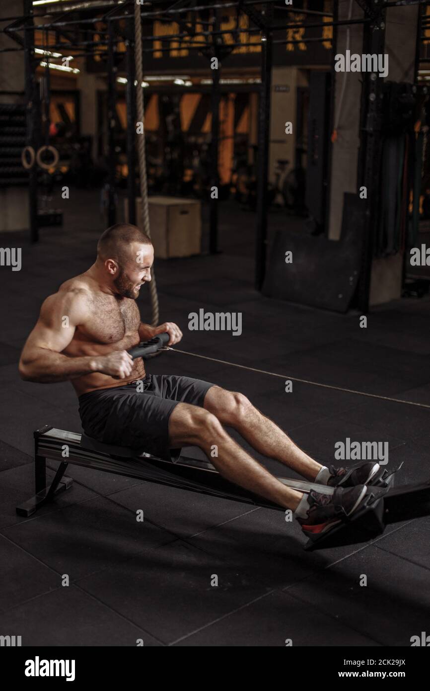 strength , power and force concept. intense exercise on rowing machine. full length photo. keep fit Stock Photo