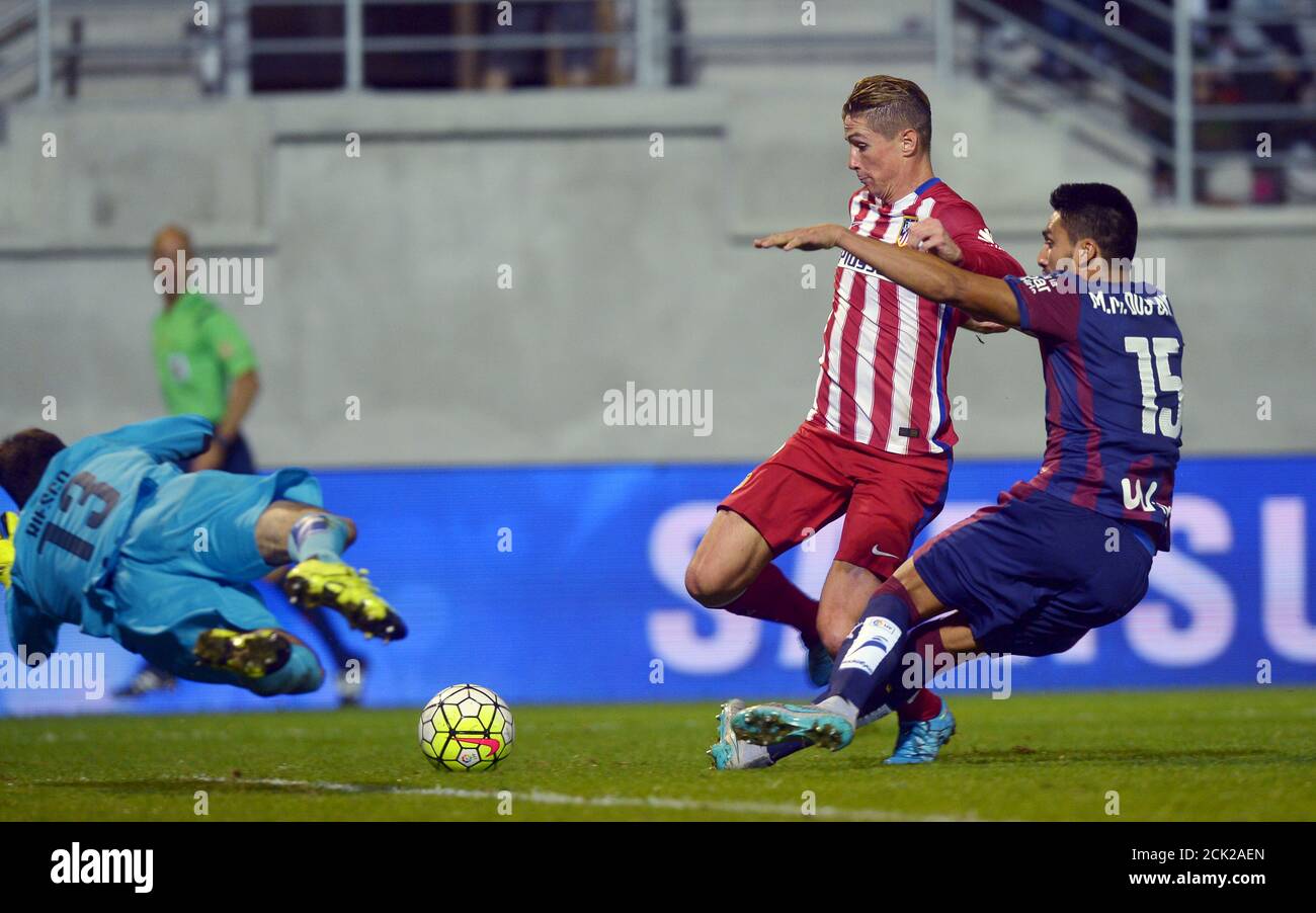 Atletico Madrid's Fernando Torres (C) passes Eibar goalkeeper Asier Riesgo  (13) and Mauro dos Santos to score during their Spanish first division  soccer match at Ipurua stadium in Eibar, September 19, 2015.