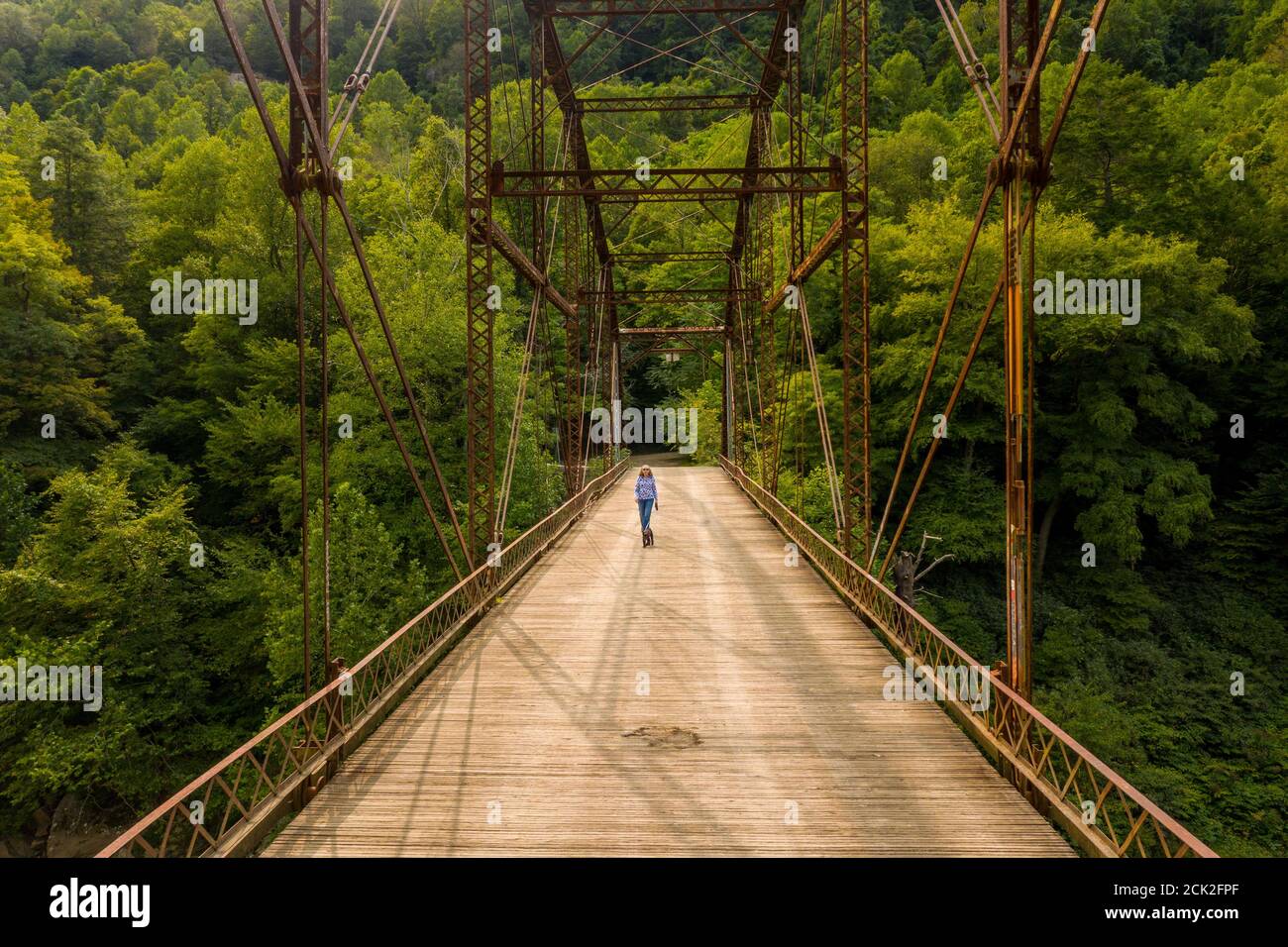 Aerial view of a senior woman walking her dog across the historic metal truss Jenkinsburg Bridge near Morgantown over Cheat River Stock Photo