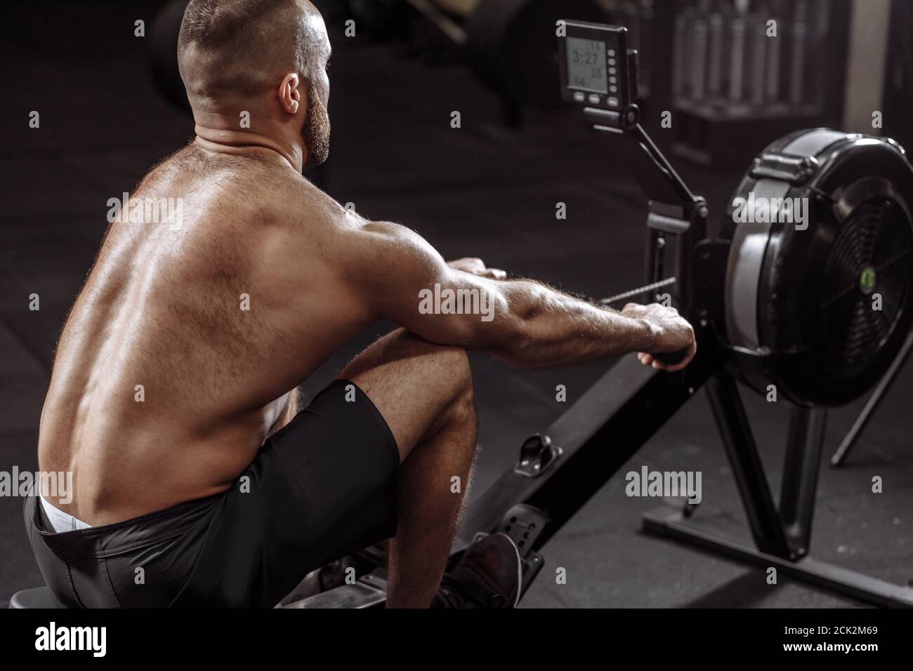 closeup back view photo of a sportsman training on row machine at gym. sport and cross fit concept Stock Photo
